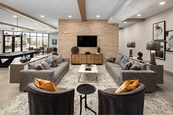 A modern living room with a brick wall and a large sectional sofa.